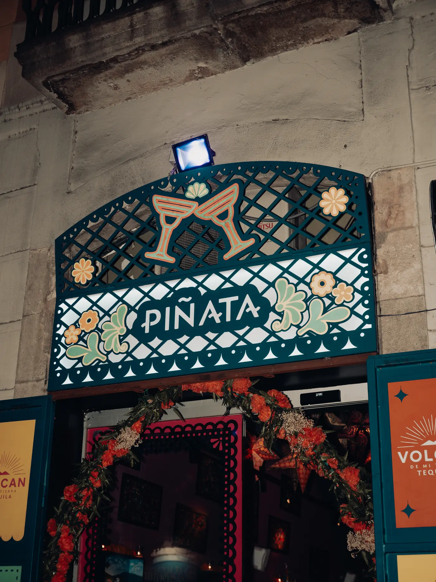 El rótulo de Piñata Cantina sobre la puerta, con azulejo verde y flores